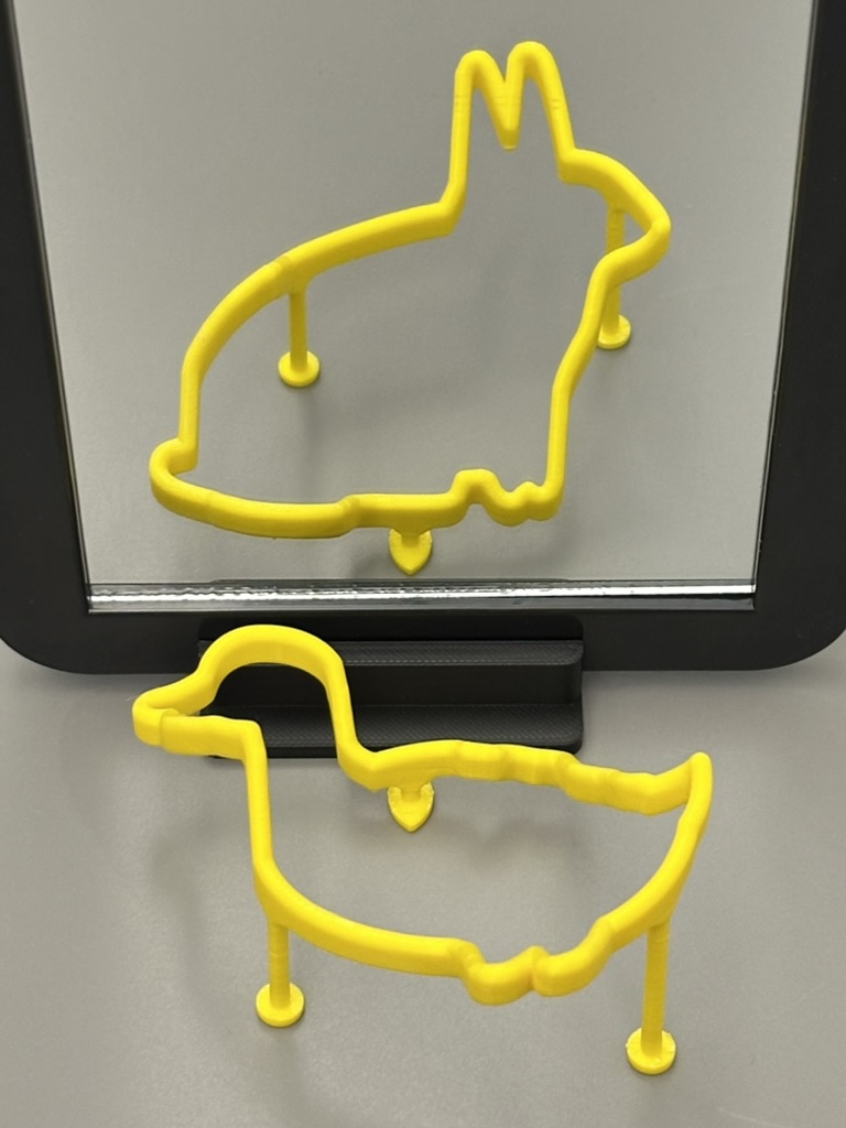 Printed impossible object viewed directly next to its reflection in a tipped mirror, showing both silhouettes at once