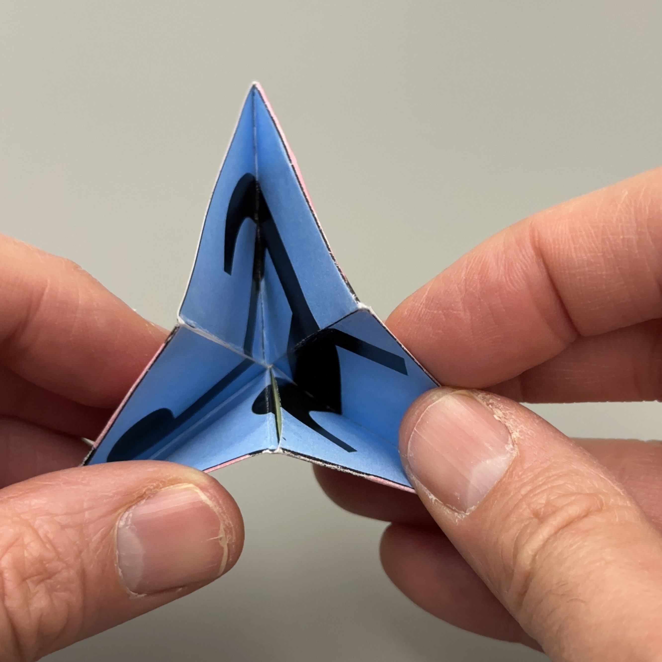 Thumbs opening the center of the pinched flexagon to reveal a new face